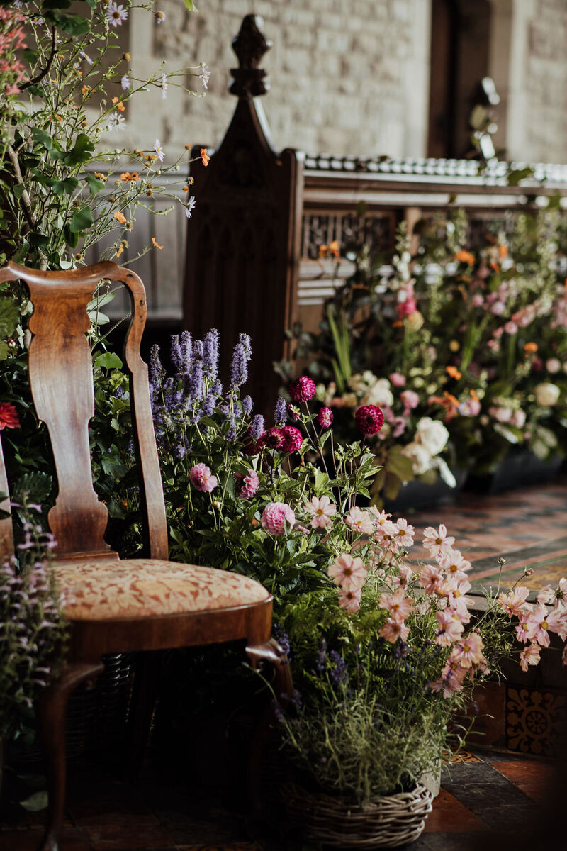 Anna Sawle is arranging a large display of flowers on a glass vase in the marquee. The flowers include coral charm peonies, purple orchids 