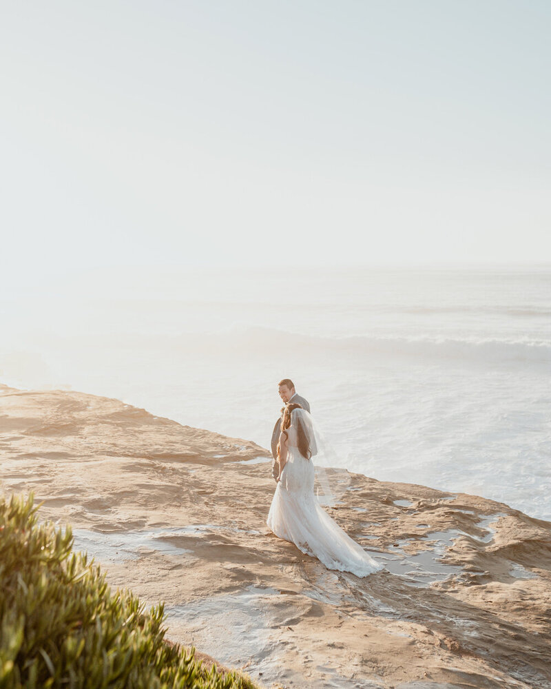 Bride and Groom walk along Sunset Cliffs in San Diego after wedding