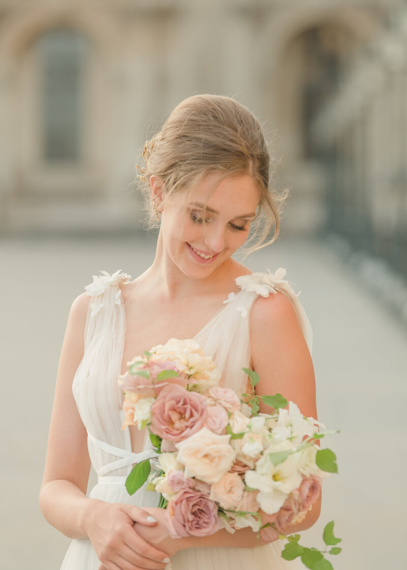 A bride in a white dress holding a white wedding bouquet.