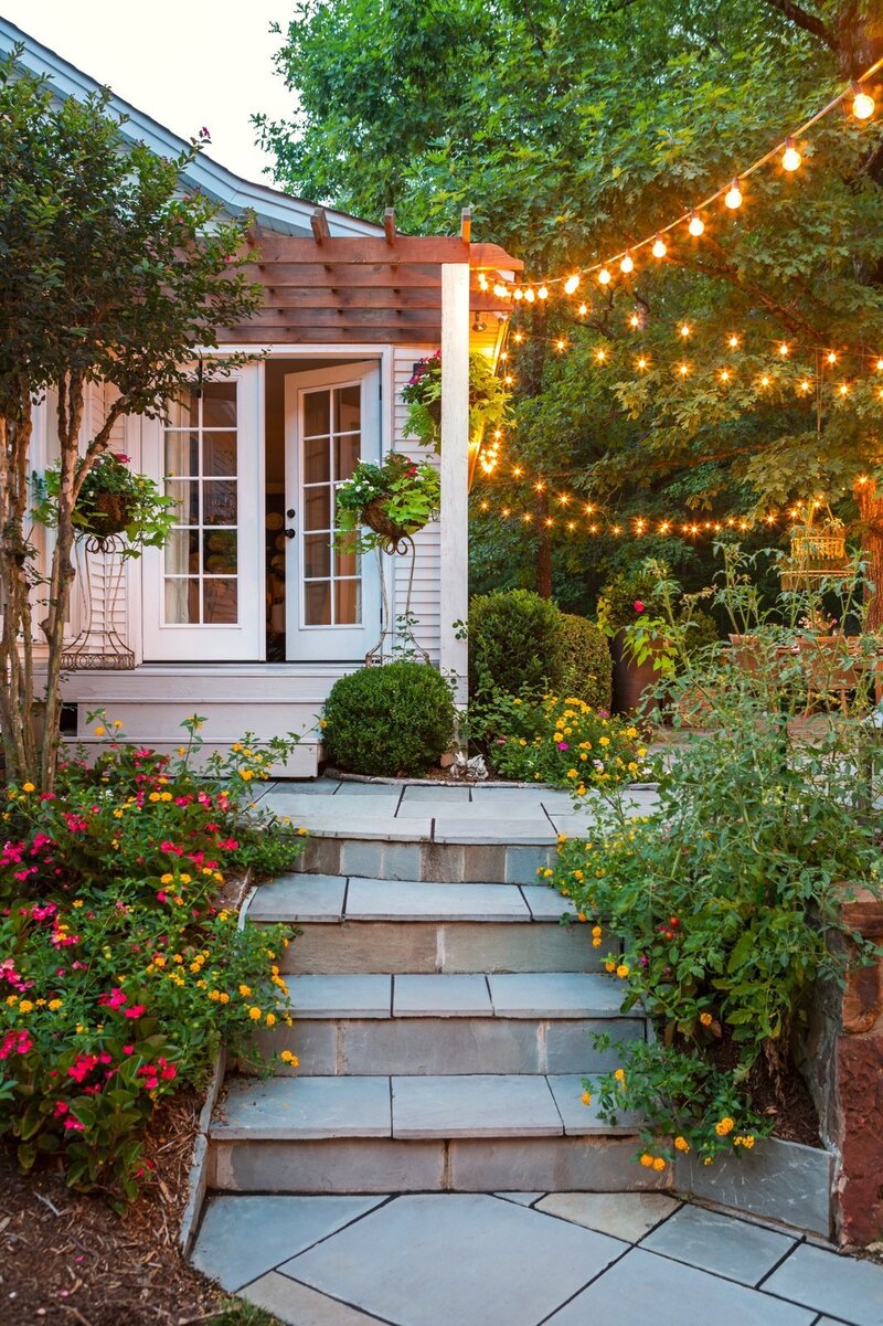 Charming garden entry with stone steps, lush plants, and glowing string lights, designed by Better Lawns and Gardens to enhance curb appeal in Little Rock, Arkansas.