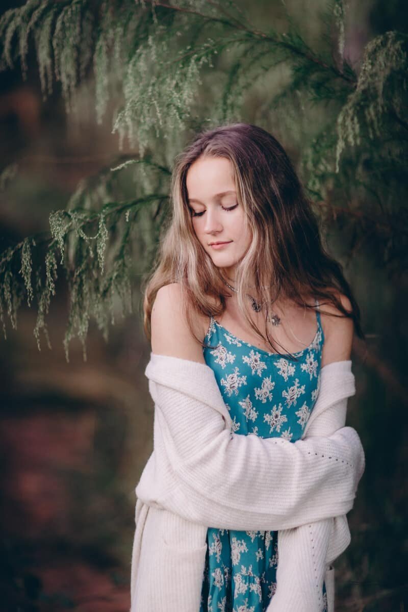 Beautiful girl looks down over her shoulder while having her senior portraits taken