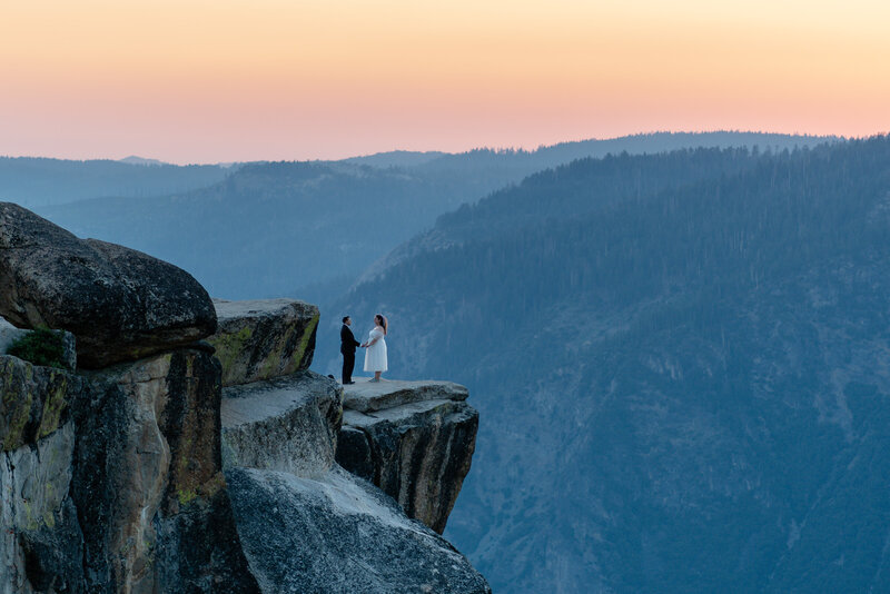 Bride and groom showing how to elope in Yosemite National Park above Taft Point during sunset vows.