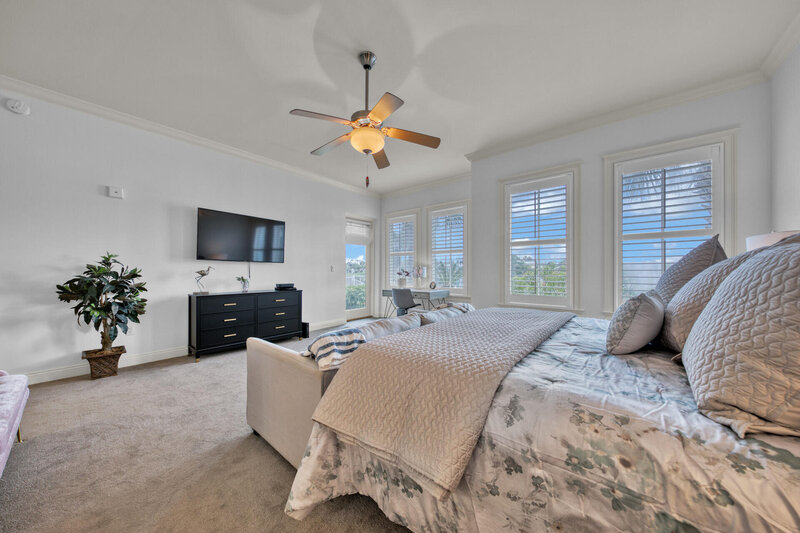large master bedroom with king bed couch and large windows
