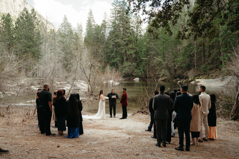A couple is eloping in Yosemite with 25 guests around them, the ceremony is surrounded by trees