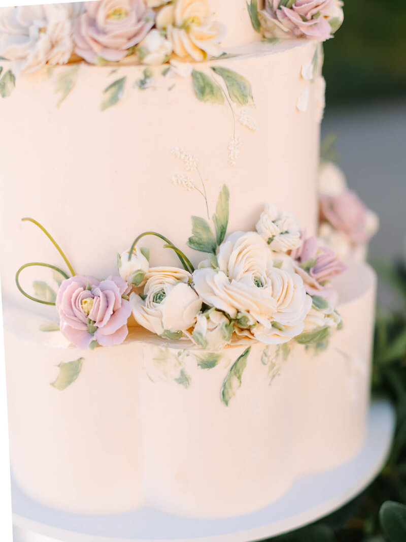 close up detail photo of cake with white, cream, and lavender rose fondant