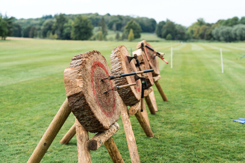 wooden archery butts in a field with thrown axes imbedded in them as an activity for a birthday party