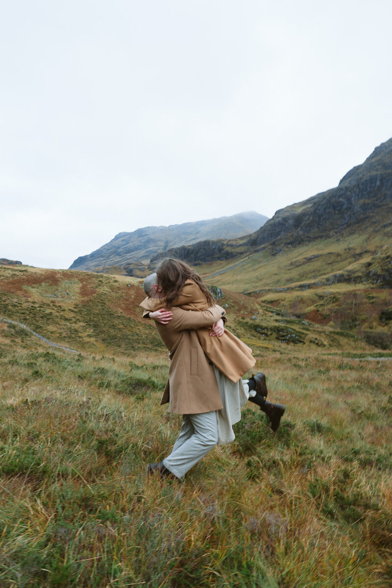 Couple on their honeymoon in Glencoe  and their share a kiss near the kingshouse hotel