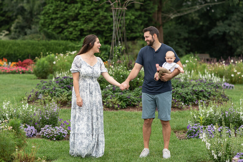 Couple in field, looking down at pregnant mom's belly
