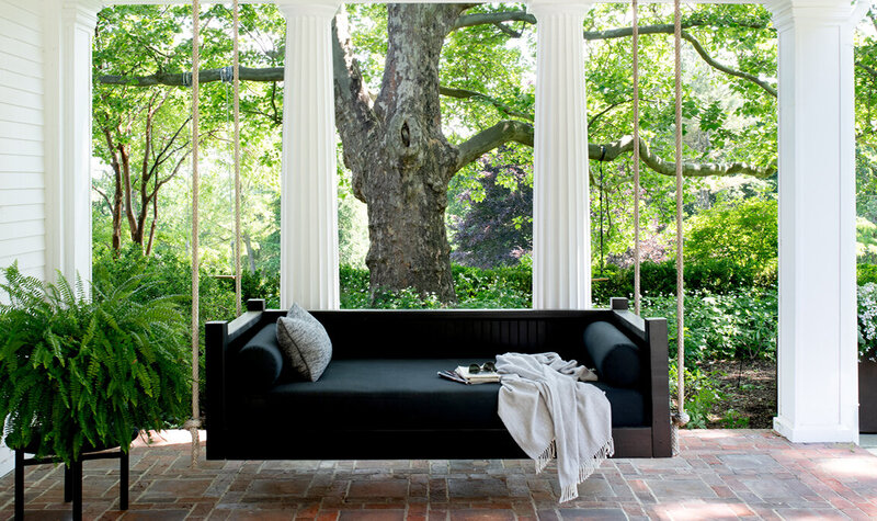 Historic home designer Boston updates a Concord patio with a modern black daybed, blending original architecture with contemporary outdoor living. 