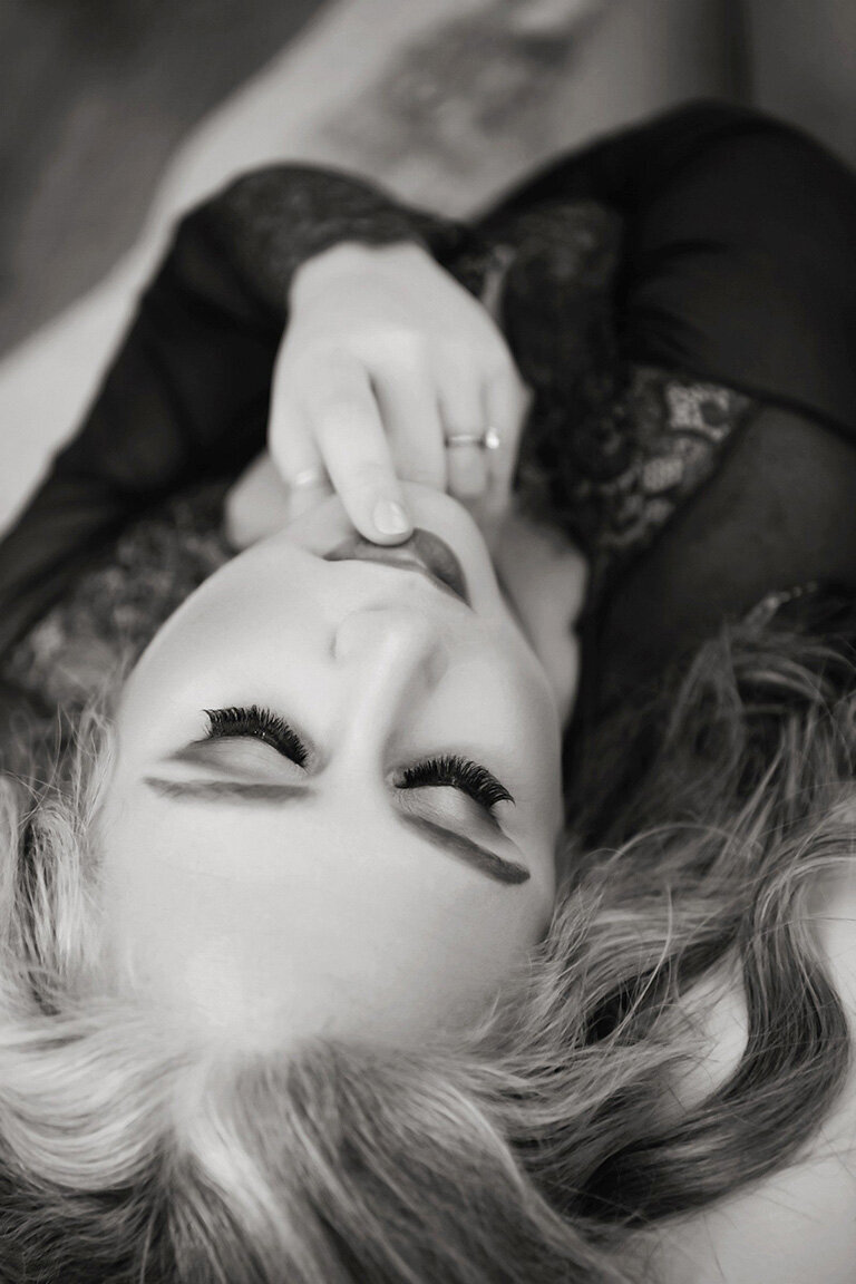 Redhead woman with tattoos poses in edgy boudoir photoshoot.