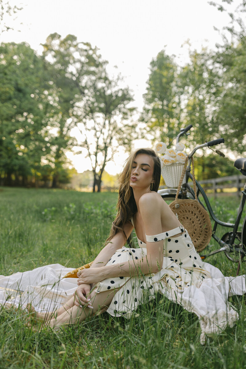 Editorial spring portrait of a woman sitting in tall grass with a vintage bicycle on a family farm in Greenville, South Carolina. Captured by Dani Lacey Photographs.