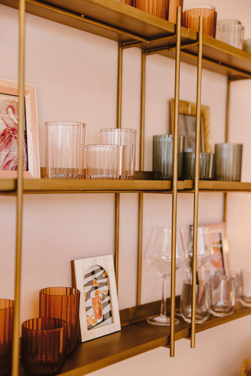 gold metal shelving with glass sets, pink wall
