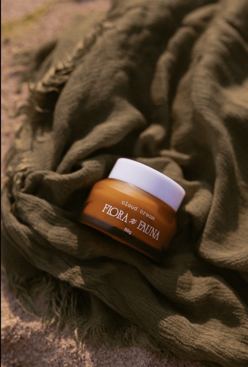 A close-up of Flora x Fauna’s night cream jar, resting on a natural fabric. The rich, earthy colors highlight the product’s organic ingredients and nourishing properties.