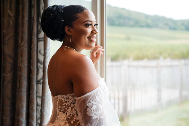 Janaya staJanaya stares out the window with a smile ceremony  before she  proudly walk down the aisle to marry her husband to be at breaux vineyard