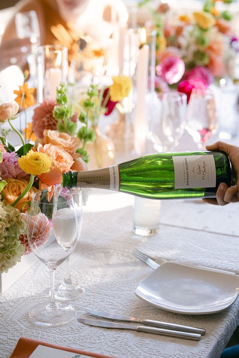 Colorado wedding planners pouring champagne for final touches to reception tables