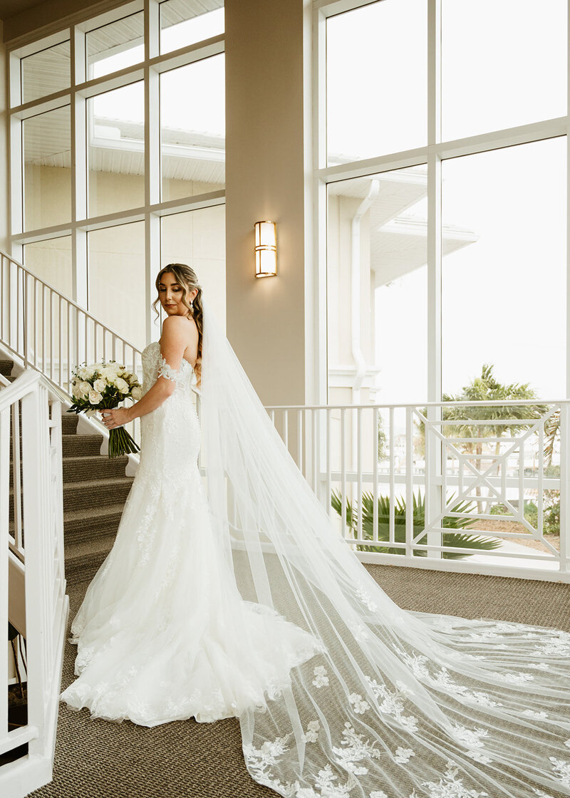 Beautiful bride on stairs showcasing dress and veil Florida