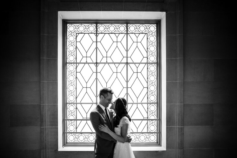 Couple silhouetted against San Francisco City Hall's decorative window with geometric pattern - wedding photographer