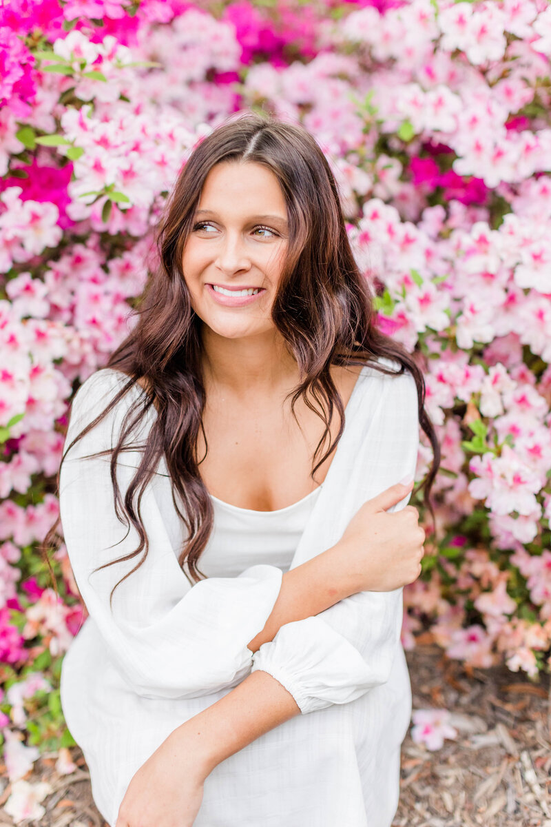 girl with white dress posing with pink flowers behind her