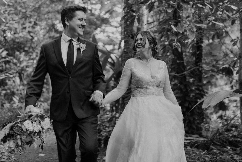 Black and white photo of bride and groom holding hands and smiling