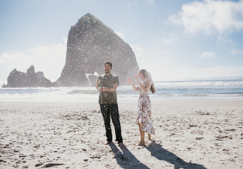 Couple walking along the Oregon Coast with sea stacks in the background, captured by an Oregon Coast Elopement and Wedding Photographer