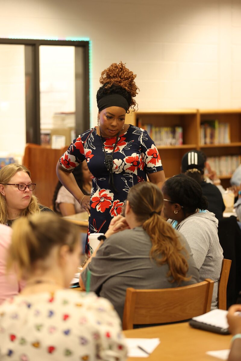 Deonna standing over educators at a table