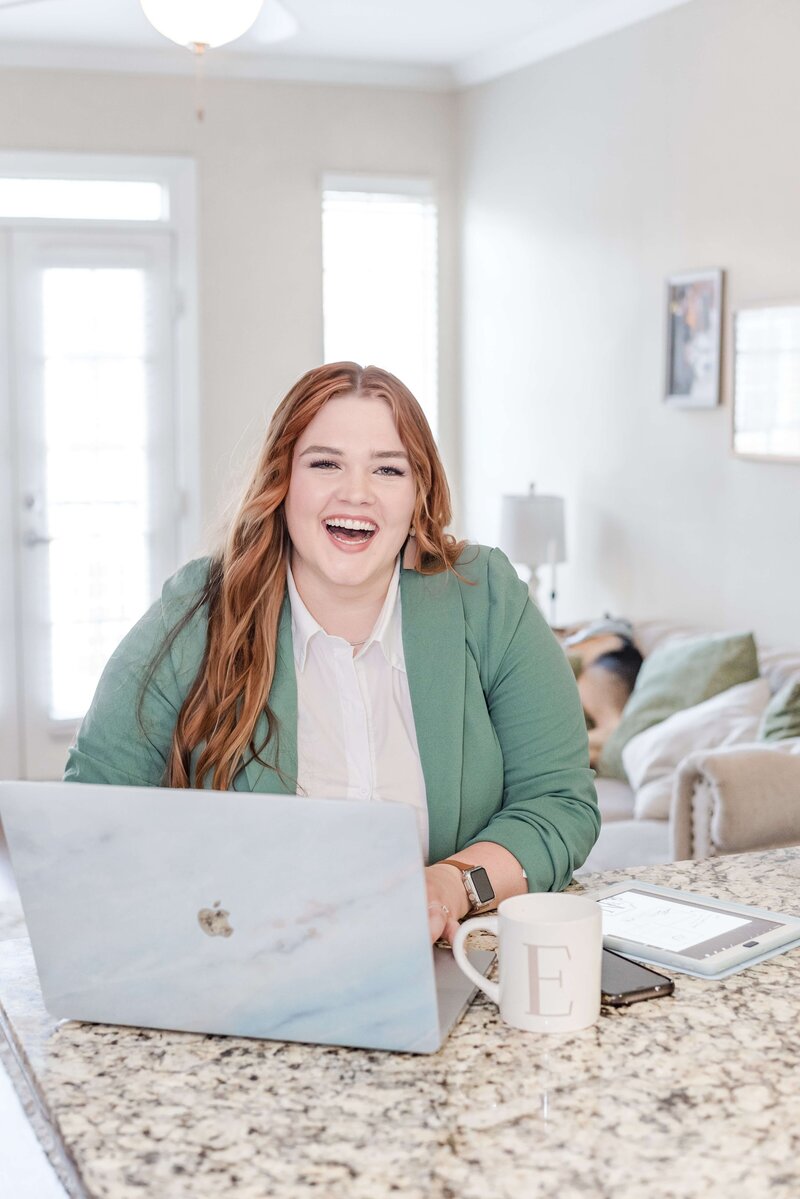 Elyse Stokes sitting with a big smile in front of her laptop, prepared for client collaboration and exceptional service