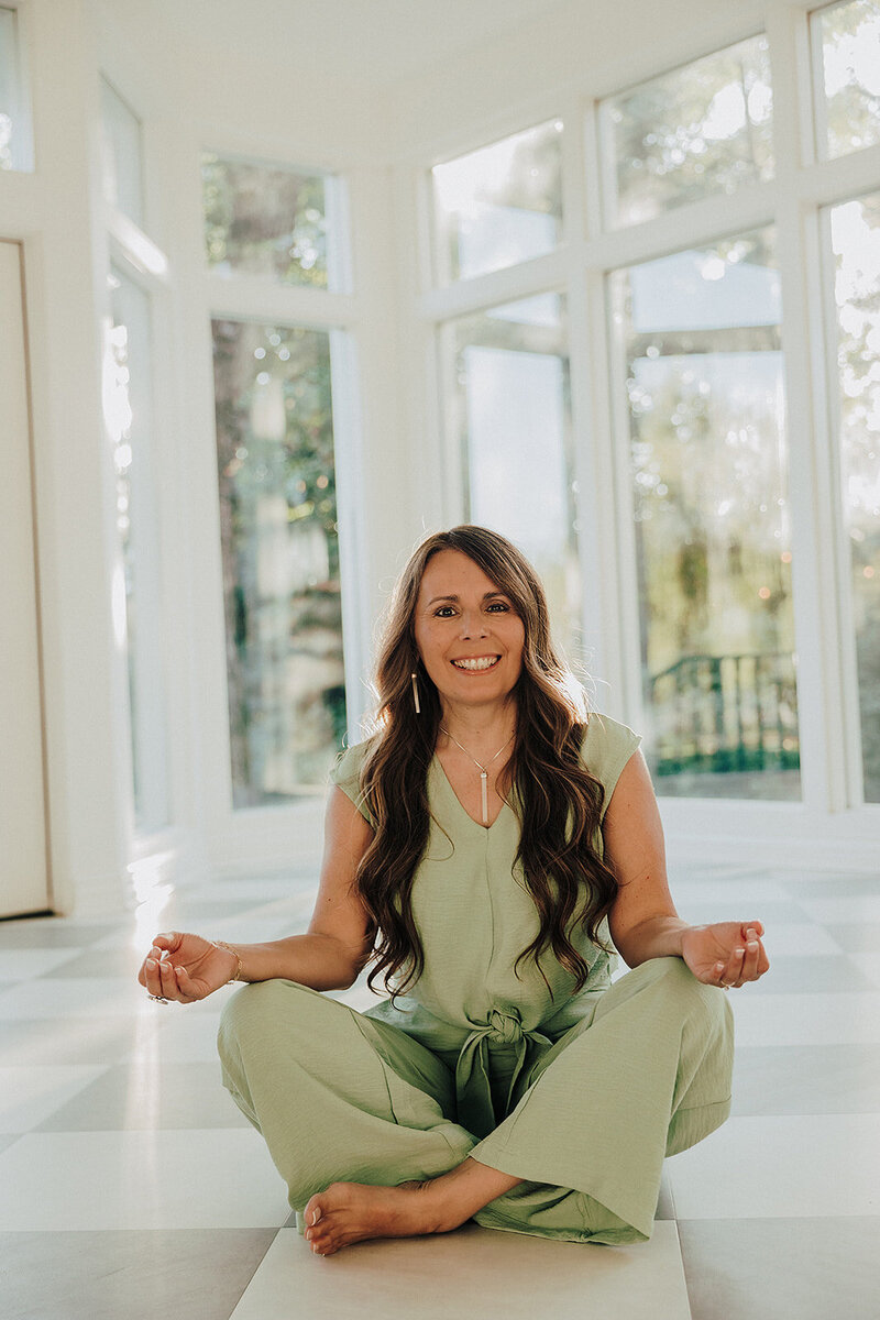 Patty wearing green and sitting cross legged on the floor 