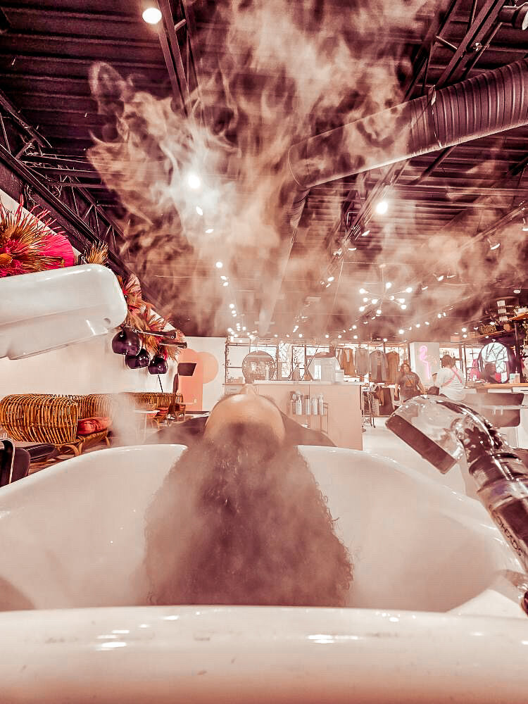 A client enjoying a soothing stream treatment on her hair at Moxie by KC