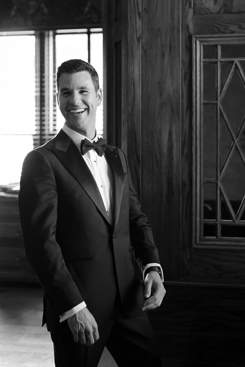 Groom dress in tux laughs on wedding day in Newport. Deborah Zoe Photography