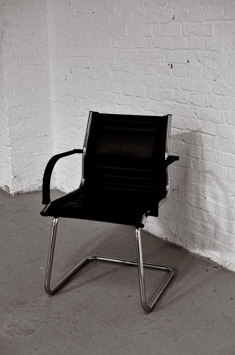 a black chair sitting in front of a white brick wall