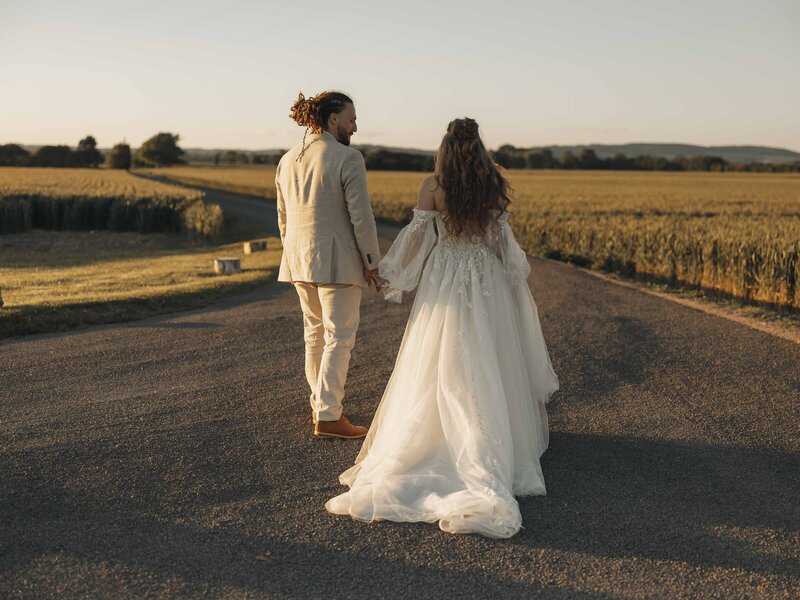 Bride and groom holding hands at sunset