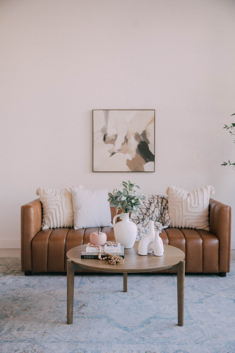 Transitional style primary bedroom staged by Modern Mollusk with soft green bedding, natural wall art, and neutral colors.