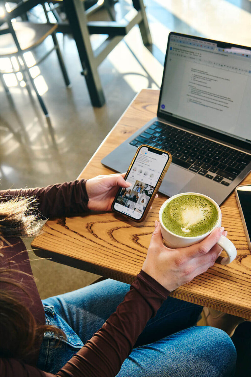 close up view of phone and green matcha with computer open