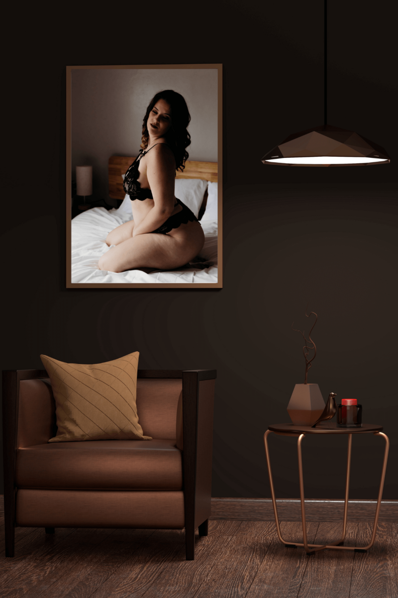 image of a woman kneeling on a bed from her Wisconsin boudoir photo session hanging above a chair in a dimly lit corner