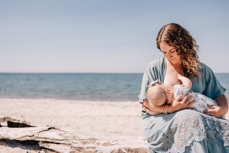 Woman breastfeeding a baby on a beach in Waterford, Connecticut.