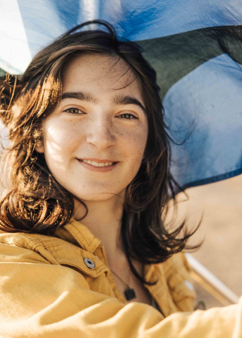 Graduating high school senior smiling and raising her color guard flag.