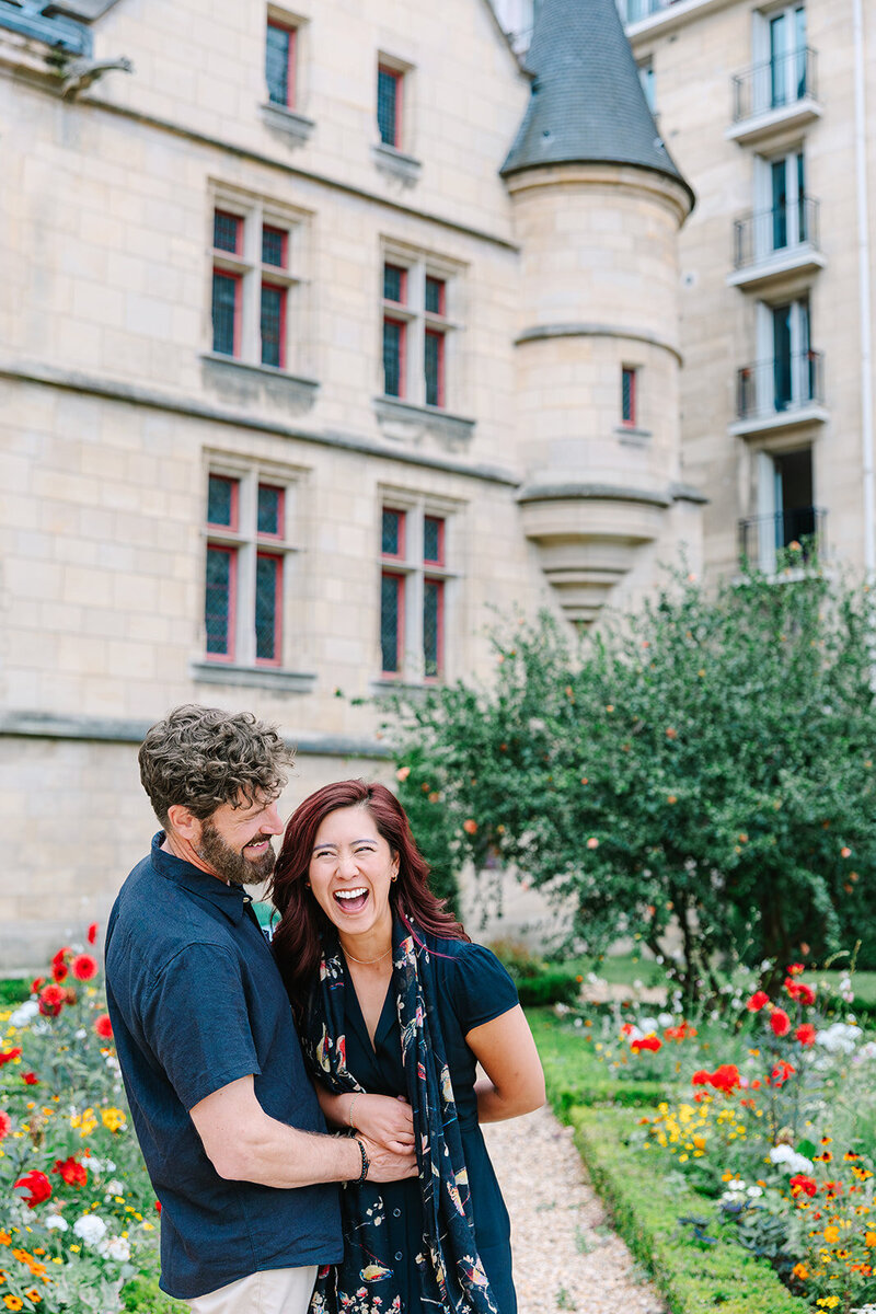 Man and woman sitting laughing at Hotel Sully during couples photoshoot in Paris