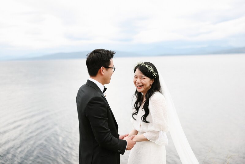 Delighted newlyweds against the stillness of the ocean on their wedding day, by Tealily photography