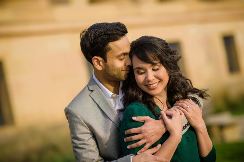 A couple bursting into laughter while wrapped in a warm embrace during their engagement session, capturing their genuine connection and happiness.
