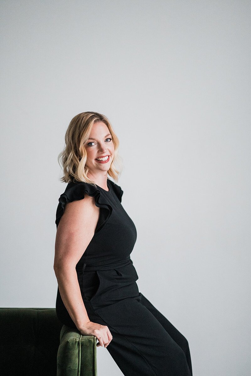 A woman sitting on the edge of a couch, smiling at the camera