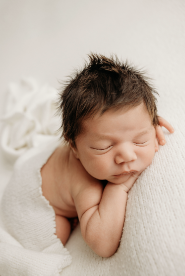 A baby with loads of brown long hair during her newborn photoshoot with auckland newborn photographer michelle kelly in her photography studio