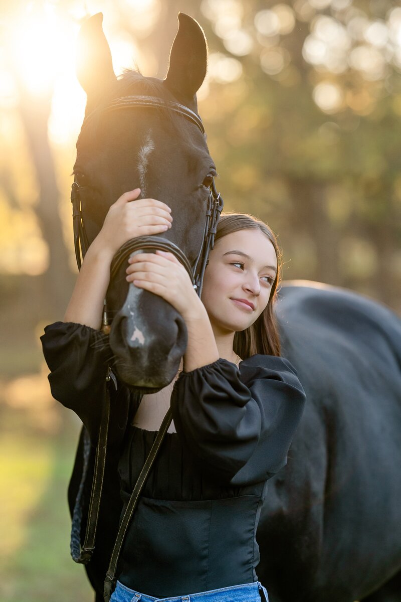 KJM the Farm riding student Aubrey Ory hugs the nose of her black  mare during an autumn equine photo shoot