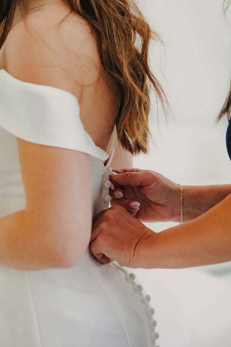 mother of the bride zipping up brides dress