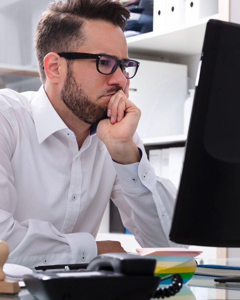 Man sitting alone in a dimly lit room, looking toward the light with a somber expression, symbolizing inner struggle and hope for healing.