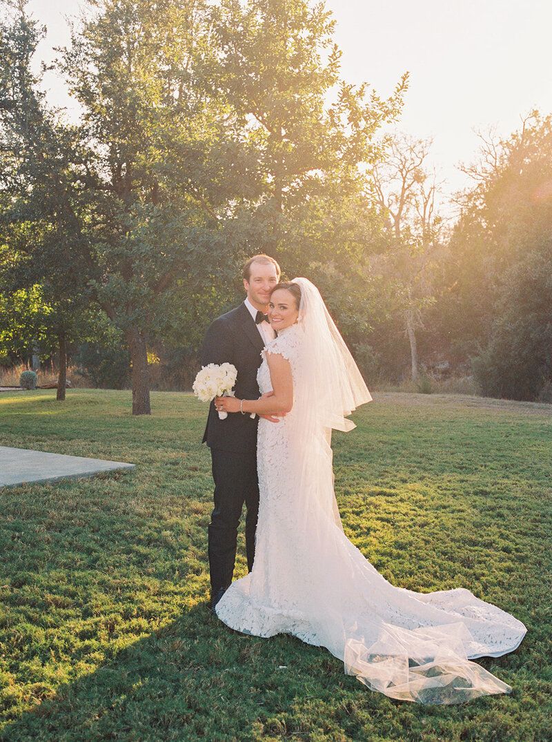 film photo of bride and groom smiling and looking at the camera with train flowing