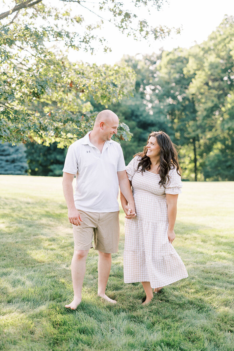 Husband and wife hold hand and hand barefoot in a Pennsylvania field