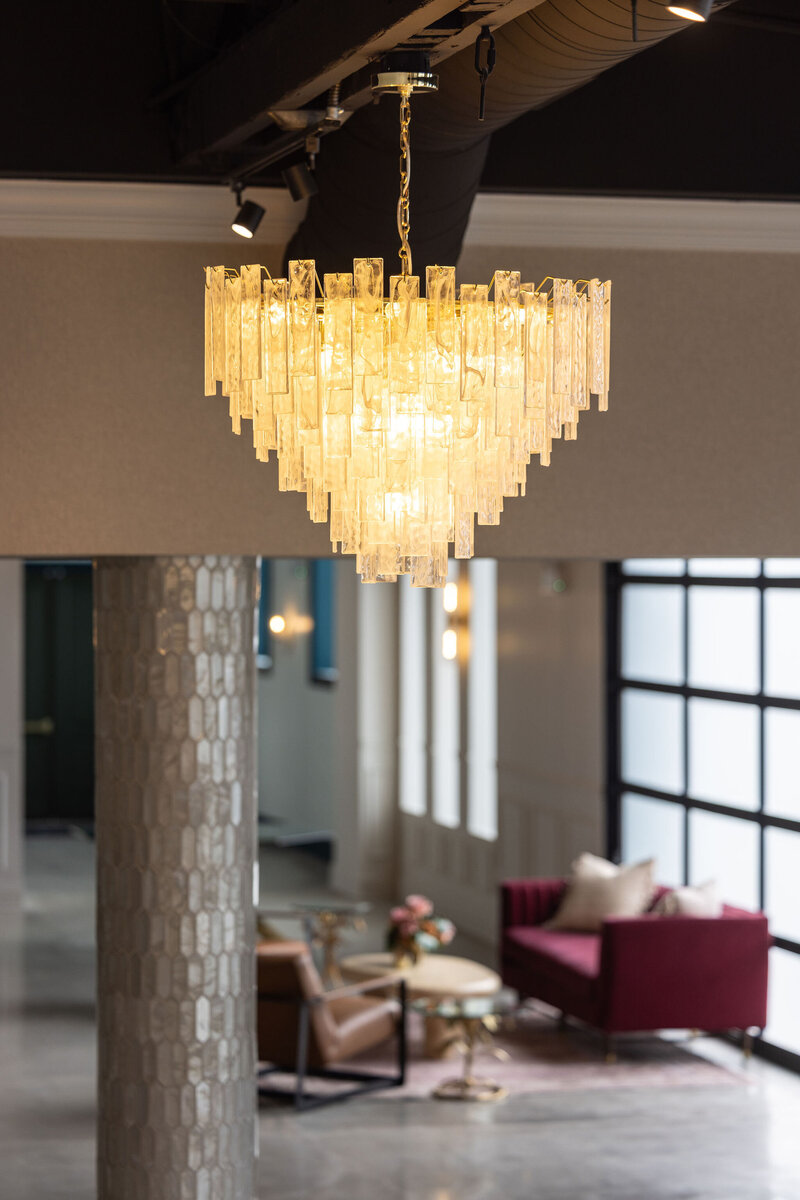 unique crystal chandelier in Happy Hour space paired with natural light from industrial-inspired garages, lighting venue beam covered in iridescent tiles