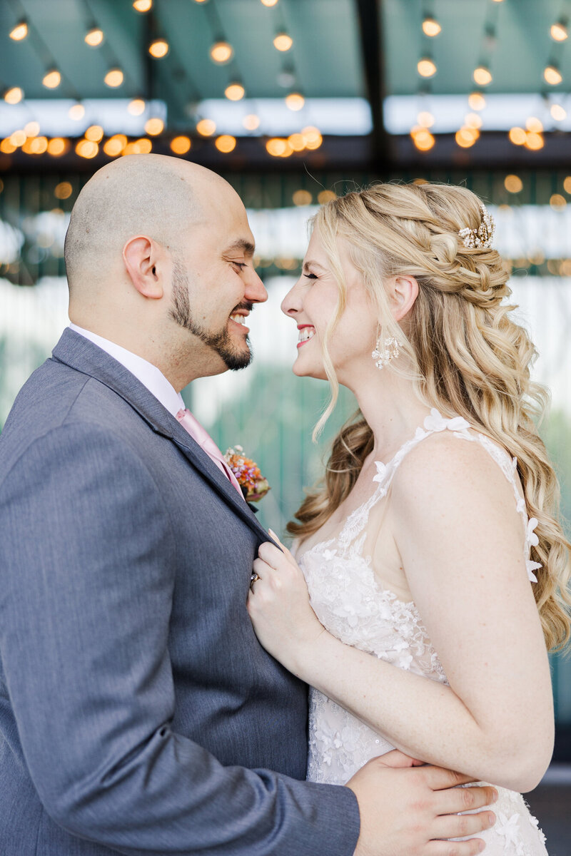 Chloe and Tony smiling nose to nose under string lights on their wedding day