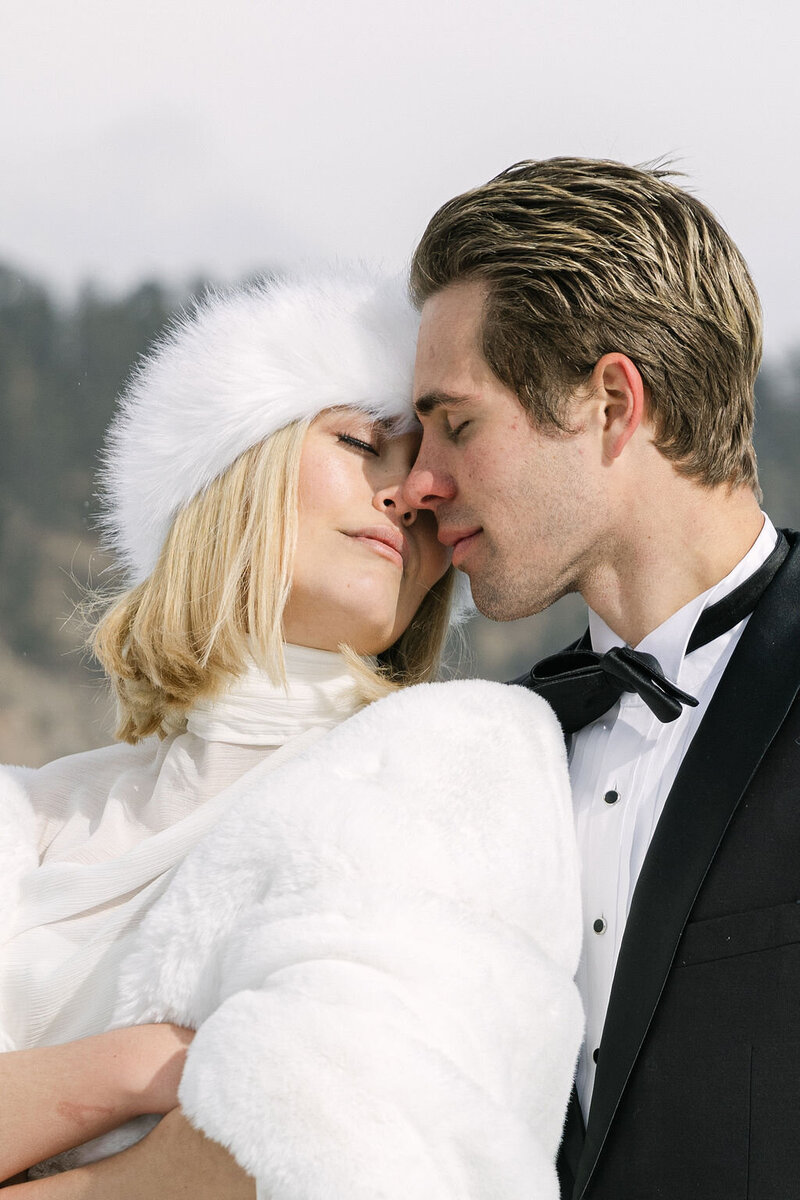Up close romantic wedding portrait of bride and groom embracing on a frozen lake at Evergreen Lake House wedding venue in Colorado