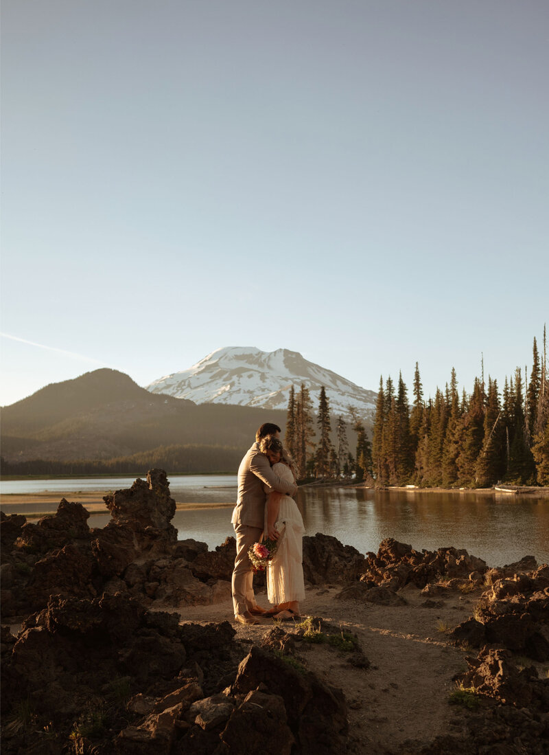 engagement couple embracing and hugging at Sparks Lake in Bend, Oregon on a beautiful sunny day